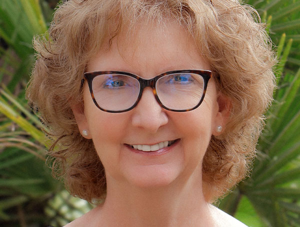 a close up of a woman wearing glasses and smiling at the camera